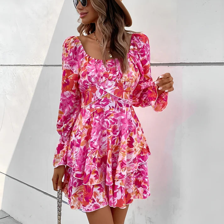 A woman wearing a knee-length midi dress with a floral pattern in pink and orange colors, with long sleeves and a square neckline.