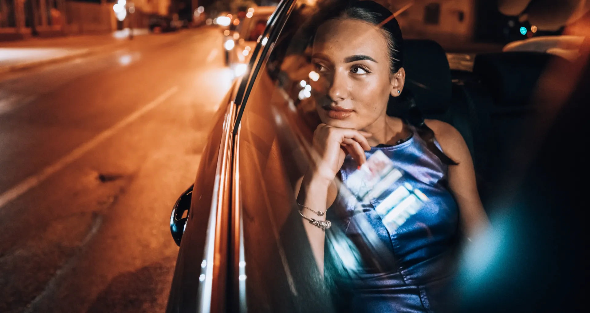 Woman sitting in a car at night wearing an evening dress